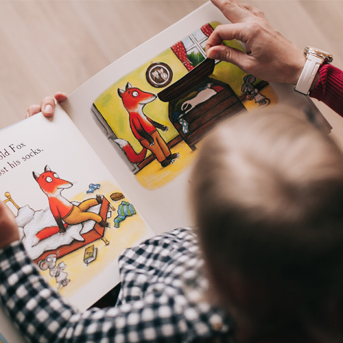 Criança a ver um livro com ajuda do adulto